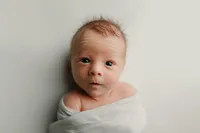 Bright-eyed newborn wrapped in white, alert and curious during a studio session with a Waukesha County newborn photographer.