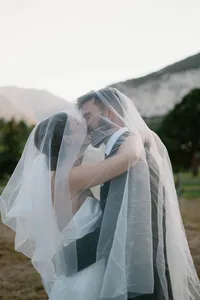 bride and groom kissing under a wedding veil with a sunset over the mountains mount princeston wedding venue