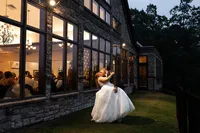 Bride and groom kissing outside of their venue in the Poconos, Pennsylvania. Guests can be seen through the windows.