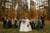 Two brides kissing as their wedding party rushes around them cheering.