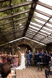 Bride and groom cheering at the end of the ceremony, before walking back down the aisle. Guests are blowing bubbles.