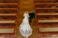 Top down balcony photo of a bride and her dad walking down the aisle in a Los Angeles church with warm yellow light.