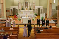 Wedding party walking down the aisle in a Los Angeles church with warm yellow light and a candid documentary feel.