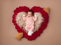 4Karma Studio - A sleeping newborn posed with a delicate heart-shaped prop in a Hollywood studio, styled with soft textures and true-to-life colors for a timeless portrait.