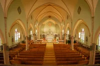 Interior of a Los Angeles church filled with warm yellow light, highlighting arches, aisle details, and ceremony atmosphere.