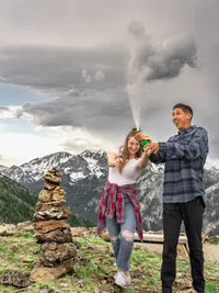 Couple celebrating a proposal near Big Bear Lake with a bottle of champagne during an outdoor engagement photo session.