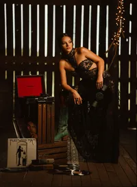 Senior portrait at Triple T Farms in Fruitdale, Alabama — leaning on her knee on wooden crates
beside an open vintage record player.