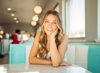 Senior portrait at Sunliner Diner in Gulf Shores, Alabama — close-up smiling with her hand
resting on her face.