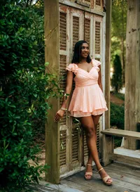 Senior portrait at Bella Sera Gardens in Loxley, Alabama — standing by wooden shutters in a
pink dress, looking off into the distance.