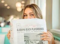 Senior portrait at Sunliner Diner in Gulf Shores, Alabama — sitting in a teal booth, peeking over
a newspaper.