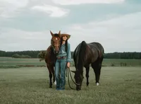 Senior portrait at Triple T Farms in Fruitdale, Alabama — posing with two horses in a field,
holding one’s head.