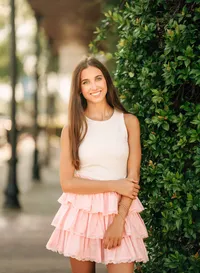 Senior portrait in downtown Foley, Alabama — waist-up near greenery, wearing a white top and
pink skirt.