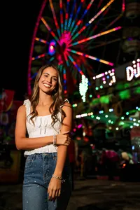 Senior portrait at the Greater Gulf State Fair in Mobile, Alabama — posing with a lit Ferris wheel
behind her.