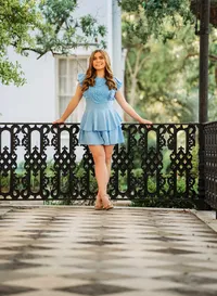 Senior portrait at the Malaga Inn in Mobile, Alabama— in a blue dress leaning against a black iron fence on the front porch.
