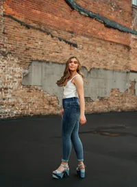 Senior portrait in downtown Mobile, Alabama — twirling her hair with a white tank top and blue jeans.