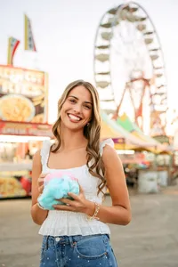 Senior portrait at the Greater Gulf State Fair in Mobile, Alabama — holding cotton candy with
the Ferris wheel in the background.