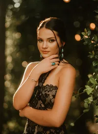 Senior portrait at Triple T Farms in Fruitdale, Alabama — black lace dress with greenery and
bokeh lights in the background.