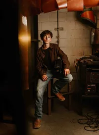 High school senior in welding gear posing in his welding teacher’s workshop near Mobile Regional Airport in Mobile, Alabama.
