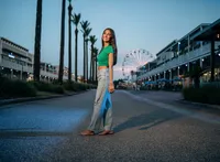 Senior portrait at The Wharf in Orange Beach, Alabama — standing in a small street with the
Ferris wheel glowing behind her.