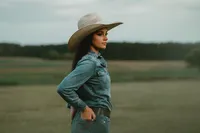 Senior portrait at Triple T Farms in Fruitdale, Alabama — denim outfit and cowboy hat, hands in
back pockets.