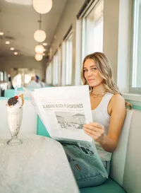 Senior portrait at Sunliner Diner in Gulf Shores, Alabama — holding the newspaper-style menu
with a milkshake on the table.
