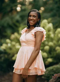 Senior portrait at Bella Sera Gardens in Loxley, Alabama — laughing in a coral dress with
limelight hydrangeas behind her.