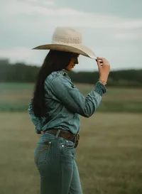 Senior portrait at Triple T Farms in Fruitdale, Alabama — side view, tipping her cowboy hat and
looking down.