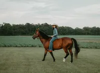 Senior portrait at Triple T Farms in Fruitdale, Alabama — riding her horse in a field.