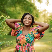 Senior girl in a floral dress posing by bright greenery in Chatom, Alabama.