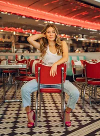 Senior portrait at Sunliner Diner in Gulf Shores, Alabama — sitting backward in a red diner chair,
holding her hair and facing the camera.