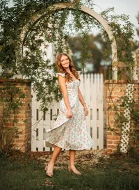 Senior portrait in downtown Magnolia Springs, Alabama — twirling her dress in front of a white picket fence.