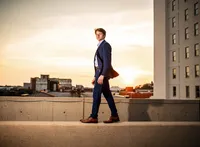 Senior portrait in downtown Mobile, Alabama— walking on a cement barrier while the wind blows the tail of his dress suit, creating a dramatic effect.