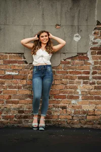 Senior portrait in downtown Mobile, Alabama — holding her hair up and standing right in front of a brick wall.
