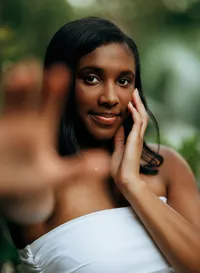 Senior portrait at Bella Sera Gardens in Loxley, Alabama — headshot reaching toward the
camera with one hand, the other hand on her face.