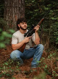 Senior portrait at Circle B Lake in Wilmer, Alabama — leaning against a pine tree holding an
unloaded hunting rifle in a ready position.