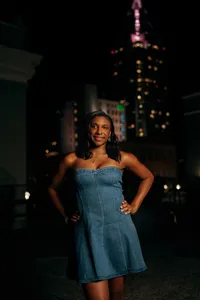 Senior portrait in downtown Mobile, Alabama — waist-up with the glowing city skyline in the
background.