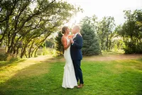 A bride and groom laugh together under sunlit cottonwood trees during their Colorado wedding.