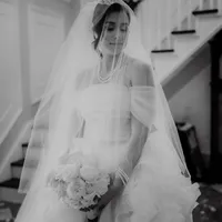 Mariée en robe blanche et voile, tenant un bouquet de fleurs, portrait en noir et blanc dans un escalier