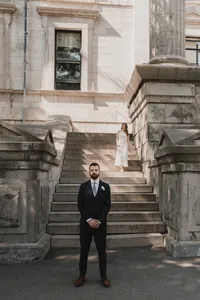 Marié attendant au pied d'un escalier de pierre monumental pendant que la mariée descend pour leur premier regard, architecture historique au Vieux-Port de Montréal
