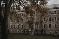 Vue cinématographique d’un couple de mariés sur le perron de l’Abbaye d’Oka, mis en scène dans une composition architecturale capturée par Jeff Gagnon photographe.
