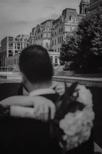 Couple de mariés enlacés, bouquet à la main, devant l’architecture historique du Vieux-Port de Montréal, capturé en noir et blanc — une image poétique et nostalgique signée par un photographe de mariage à Montréal, mettant en valeur la connexion et l’élégance urbaine du lieu.