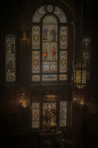 Vitraux historiques ornés de personnages médiévaux, boiseries sombres et lampe suspendue en fer forgé, détail architectural du Mount Stephen