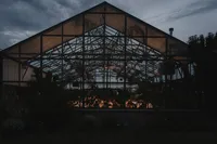 Vue extérieure de la serre vitrée d'Aquatopia à Ottawa, structure en acier éclairée de l'intérieur, invités visibles à travers les fenêtres, ciel crépusculaire