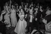Mariée dansant avec son père entourée d'invités en liesse à la Gare Viger, ambiance festive et spontanée en noir et blanc, moment de célébration familiale