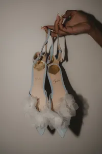 Détail des souliers de mariée bleu pâle ornés de fleurs en tulle, suspendus par leurs brides, préparatifs de mariage au Four Seasons Montréal