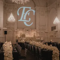Salle de réception élégante à la Maison Principale avec arrangement floral blanc, lustres de cristal et initiales en lettres géantes