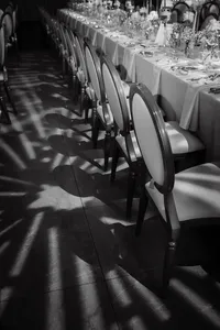 Lumière naturelle projetant des ombres graphiques de chaises élégantes alignées, à côté d’une table dressée, dans l’ambiance feutrée et poétique du Théâtre Saint-James à Montréal.