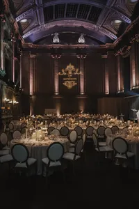 Salle de réception grandiose au Théâtre St-James à Montréal, tables rondes aux chandelles, monogramme des mariés projeté au mur, chaises médaillon élégantes