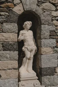 Statue de pierre classique nichée dans une alcove voûtée en pierres des champs au Château St-Agnès, détail architectural du domaine