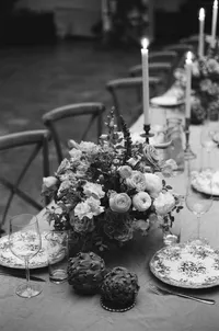 Centre de table floral abondant aux tons pastel, chandeliers et vaisselle fleurie, chaises en X en arrière-plan, décor de réception au Cathcart, Montréal